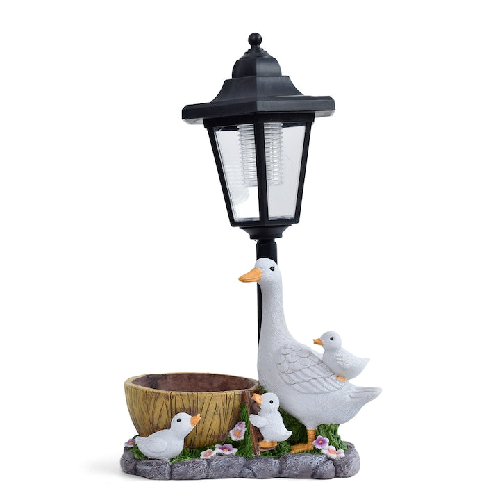 Lumini solare decorative pentru gradina si terasa asca alba mare sta sub un felinar cu puii ei Exista si un mic ghiveci de flori unde isi poate planta florile si plantele preferate Ornament pentru vila si gradina Potrivit pentru curti peluze